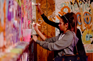 Jessica Dilling, an SU student, paints her name on a wall inside Hungry Chuck's.